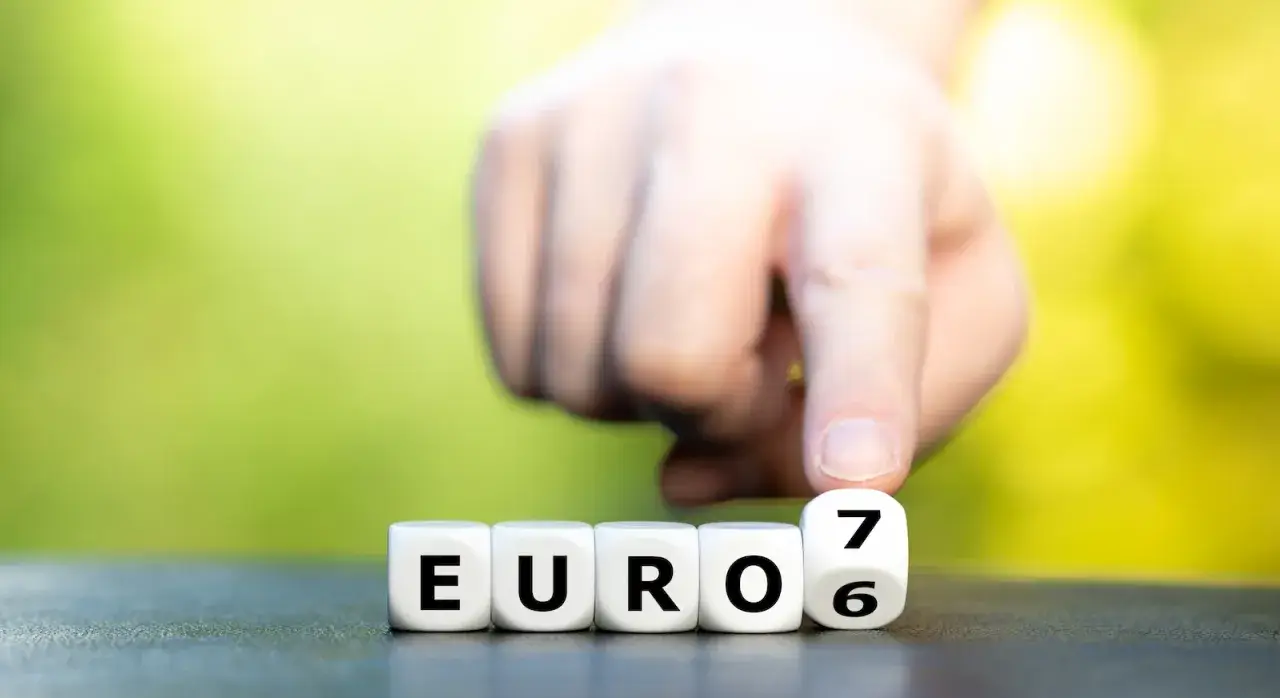 Dłoń przesuwa kostkę z cyfrą 7, tworząc napis "EURO 6", symbolizujący nowe normy emisji spalin.