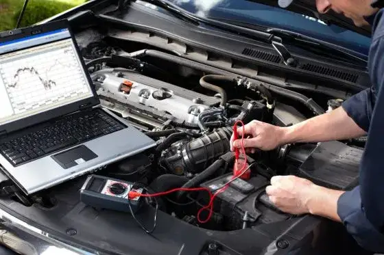 mechanik podłącza komputer diagnostyczny do samochodu